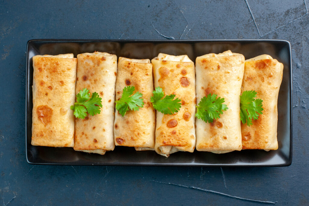 top-view-delicious-lavash-wraps-black-plate-dark-blue-background